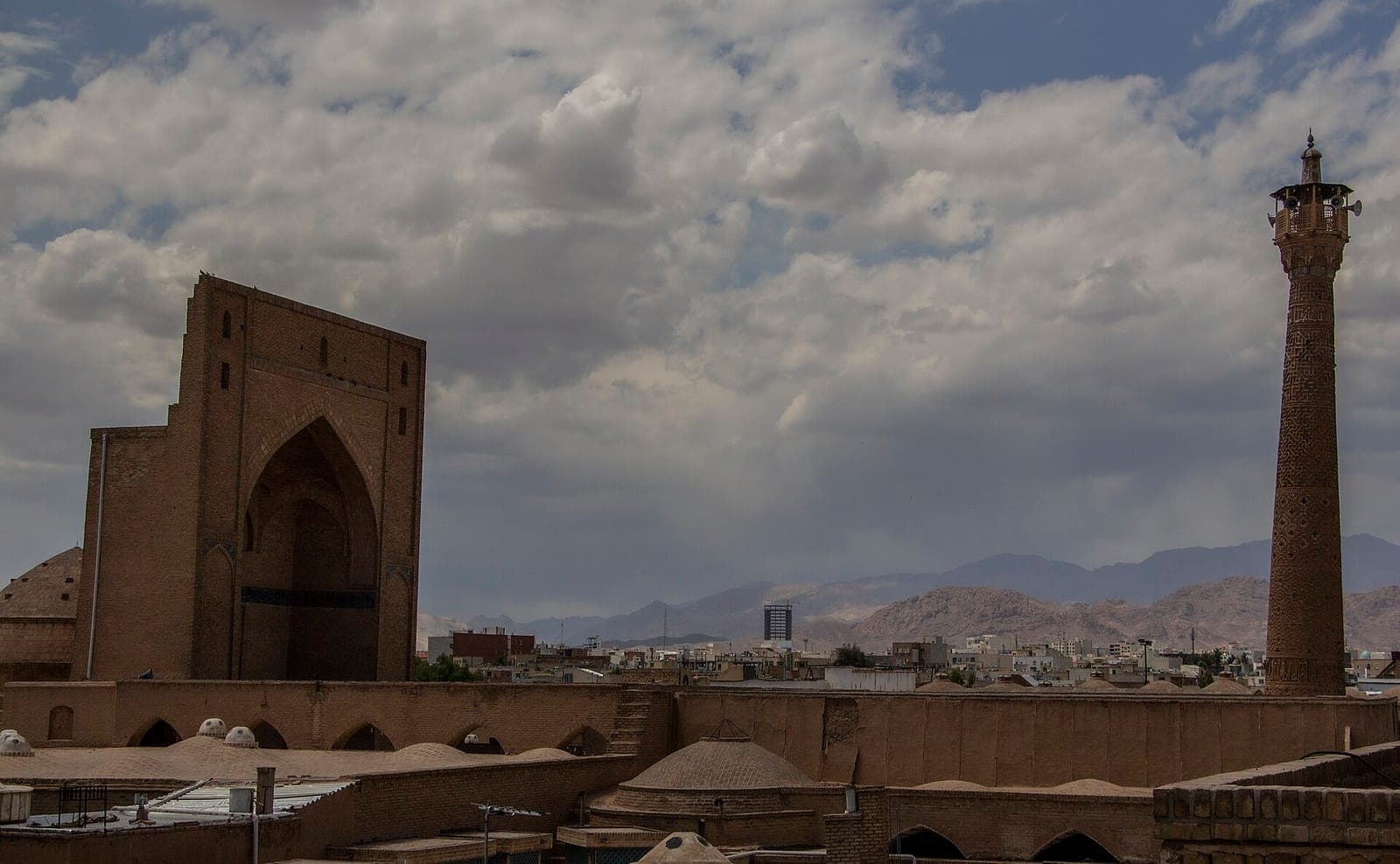 ایوان بلند آجری و منارهٔ سلجوقی مسجد جامع سمنان بر فراز بامهای گنبدی بافت تاریخی شهر