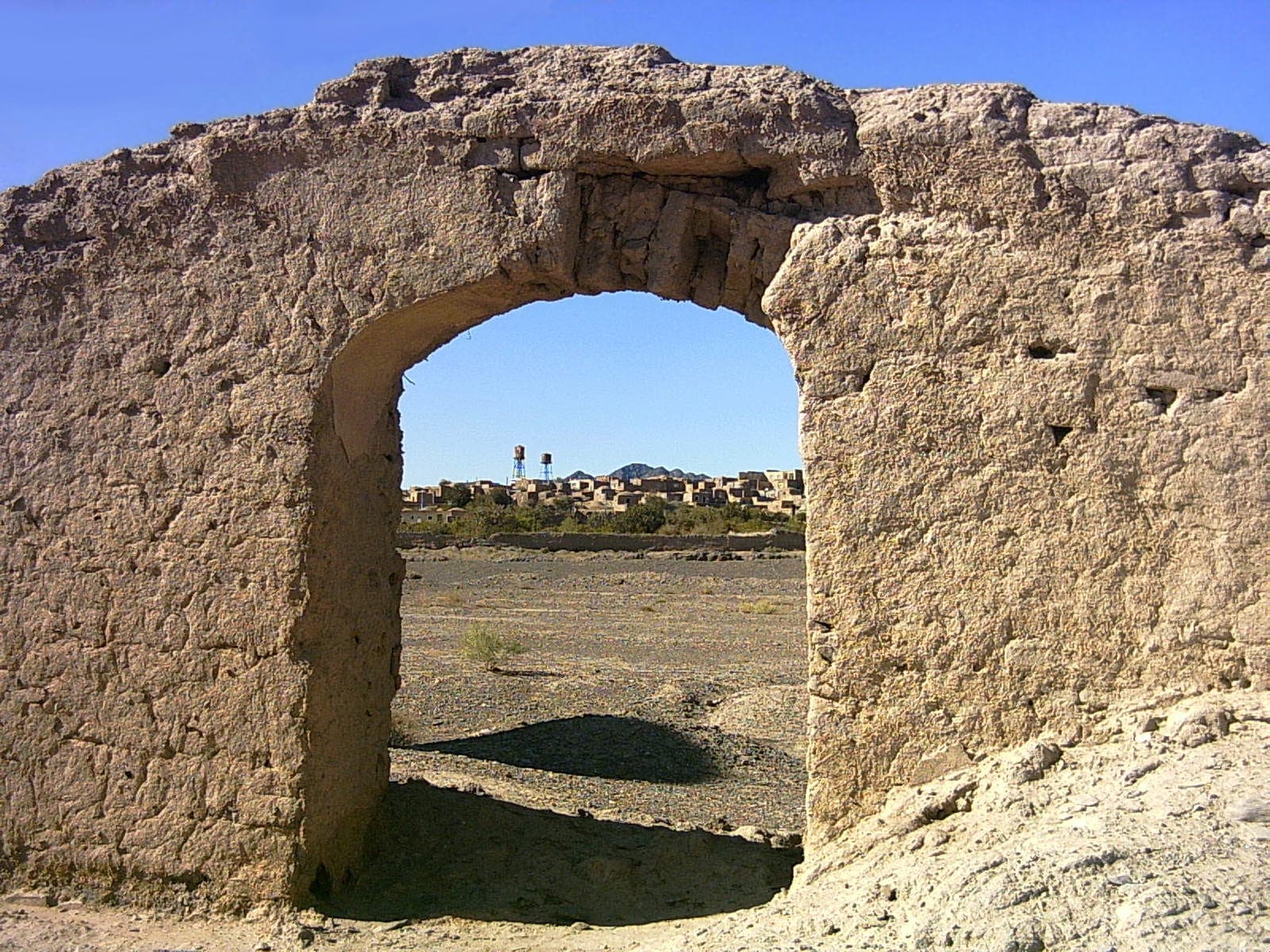 روستای عباسآباد میامی از میان طاق خشتی کهن؛ خانههای روستا و گلدستهٔ مسجد در افق