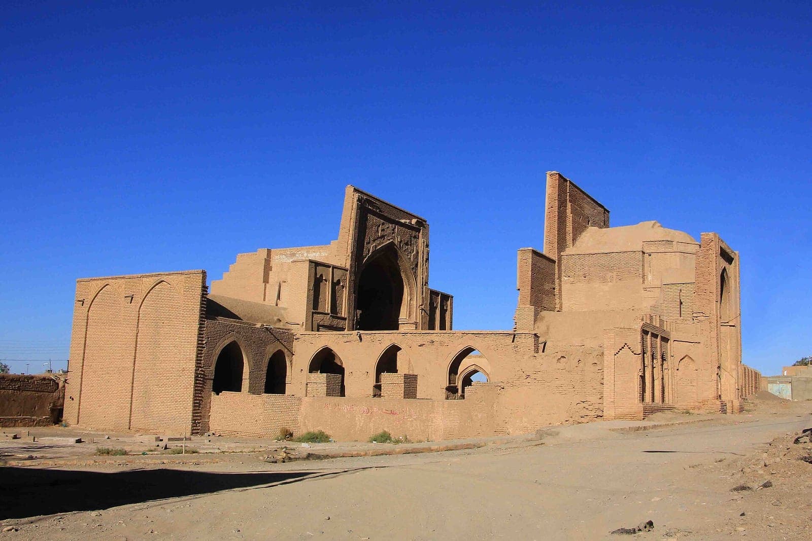 نمای بیرونی مسجد جامع فرومد با ایوانها و بام آجری زیر آسمان آبی